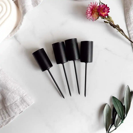 Handgemachtes DIY-Set mit taupefarbenen Stabkerzen und schwarzen Halterungen für stilvolle Dekoration.