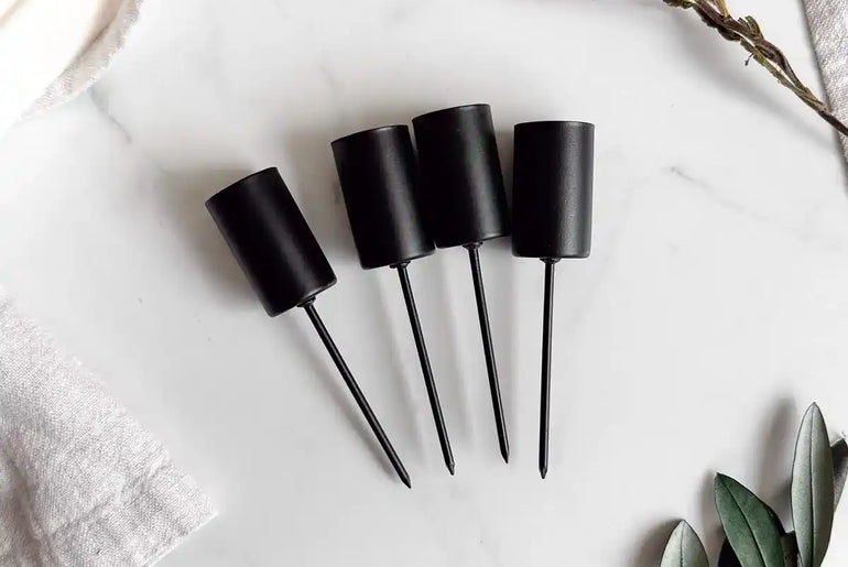 Handgemachtes DIY-Set mit taupefarbenen Stabkerzen und schwarzen Halterungen für stilvolle Dekoration.
