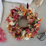 Tischkranz Nele von oben: gesteckter Trockenblumenkranz in Beere, Orange, Rot und Creme mit Moos