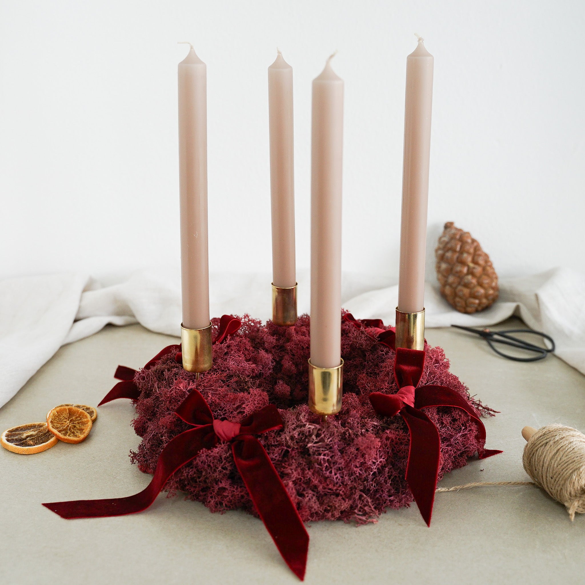 DIY-Set Adventskranz Gloria in der Variante beige/gold: dunkelrotes Moos mit beigen Stabkerzen, goldenen Kerzenhaltern und Samtschleifen