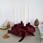 DIY-Set Adventskranz Gloria in der Variante wollweiß/schwarz: dunkelrotes Moos mit wollweißen Stabkerzen, schwarzen Kerzenhaltern und Samtschleifen